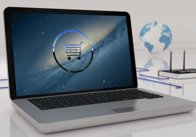 Laptop open on a laptop with a virtual representation of a shopping cart against a starry sky on the screen.