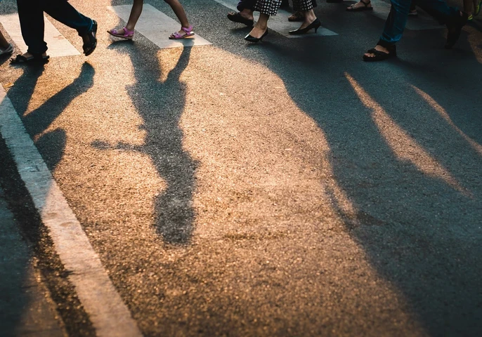 Shadows of people walking across a crosswalk.