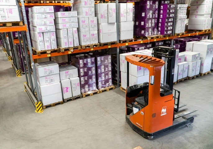 Inside of a warehouse with a forklift in front of a storage unit.