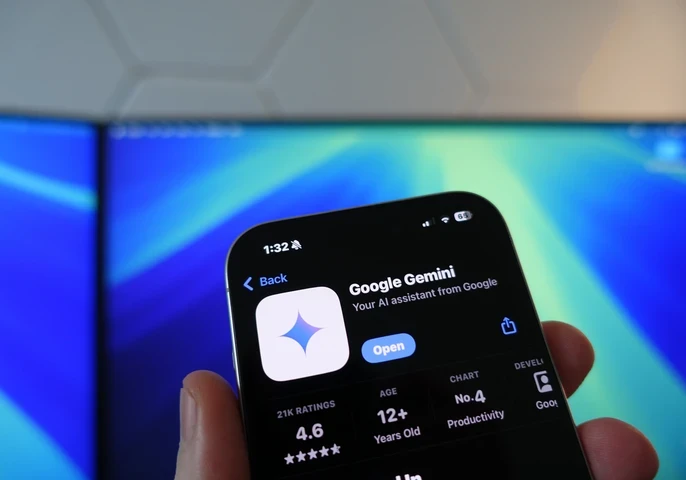 google gemini  app store screen on iphone in front of computer monitor with blue screensaver