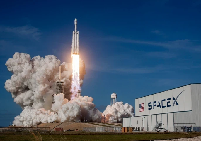 Rocket takes off with a plume of smoke on a blue sky on the SpaceX premises.