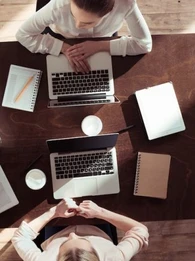 Colleagues working on laptops sharing a desk