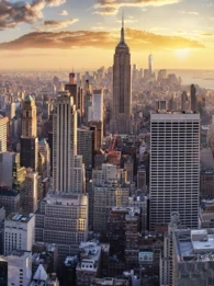 Aerial view of city skyscrapers with a sunset in the background.