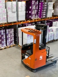 Inside of a warehouse with a forklift in front of a storage unit.