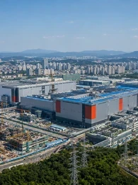 Aerial view of a large South Korean semiconductor manufacturing complex, with the headline &ldquo;South Korea Sets Record 2027 Budget as AI Chip Boom Lifts Tax Revenue.&rdquo;