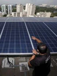 Engineer fitting solar panels to the roof of a skyscraper with the Singapore cityscape in the background