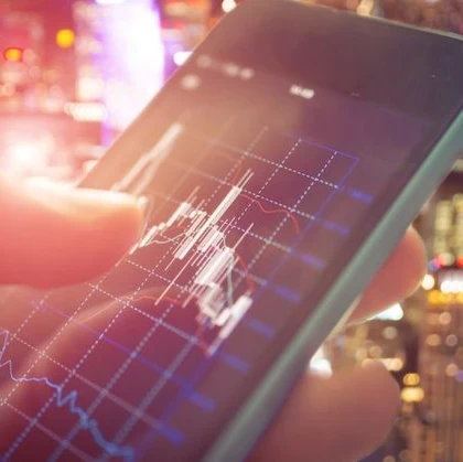 Someone using a smartphone checking stocks with a graph on a downward trend