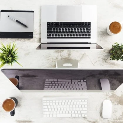 macbook and iMac computer on a desk with apple mouse and keyboard, and apple magic trackpad
